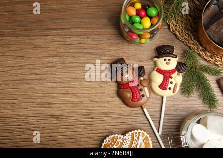 Composizione piatta con divertenti caramelle di nevi al cioccolato su tavola in legno. Spazio per il testo Foto Stock