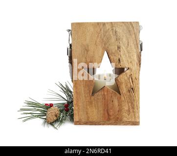 Lanterna di Natale in legno con candela bruciante vicino al ramo di abete e cono di pino su sfondo bianco Foto Stock