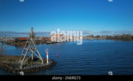 Pittoresca cittadina portuale e uno storico edificio dell'Ammiragliato. In primo piano la luce del porto di Hoorn sul blu Markermeer Foto Stock