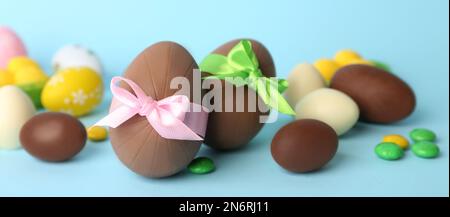 Uova di cioccolato dolce e caramelle luminose su sfondo azzurro. Design del banner Foto Stock