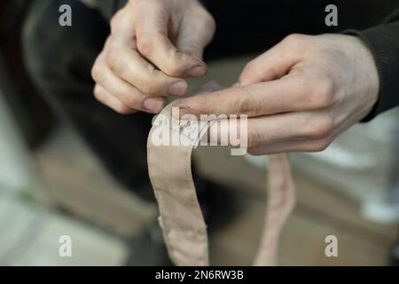 Nastro per cucire. Colletto cucito in esercito. Lavoro di tessitore. Riparare gli abiti con le mani. Foto Stock