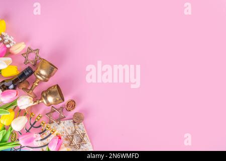 Pasqua, Pesah sfondo. pasqua ebraica Pasqua festa primaverile, con accessori - menorah, matzo, fiori primaverili, bottiglia di vino, oro wi Foto Stock