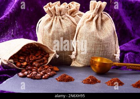 Sacchi di Hessian pieni di chicchi di caffè torrefatto con mucchi di caffè appena macinato Foto Stock