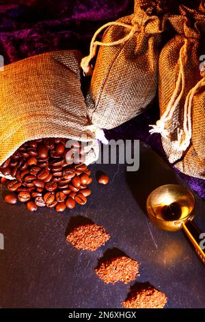 Sacchi di Hessian pieni di chicchi di caffè torrefatto con mucchi di caffè appena macinato Foto Stock