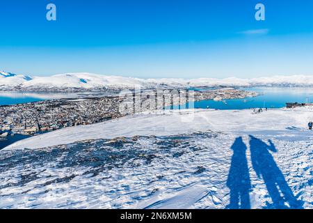 Ombra di una coppia in piedi sulla cima del monte Storsteinen che domina la città di Tromso nel nord della Norvegia, spazio copia Foto Stock