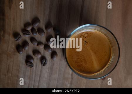 Chicchi di caffè arrosto con espresso in tazza di vetro, vista dall'alto Foto Stock