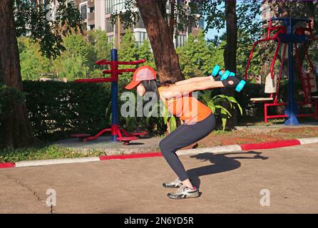Donna che fa l'addestramento del peso alla luce del sole di mattina Foto Stock