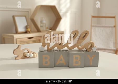 Frase decorativa Hello Baby su tavolo bianco nella stanza del bambino. Design degli interni Foto Stock