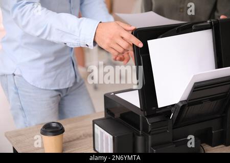 Dipendente che utilizza una stampante moderna in ufficio, in primo piano Foto Stock