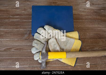 Immagine di un kit di pronto soccorso, un paio di guanti da lavoro e un martello da muratore. Riferimento agli infortuni sul lavoro. Foto Stock