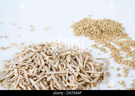 Spaghetti di uova fatti in casa non cotti e grani di grano bulgur grossolani isolati su fondo bianco. Foto Stock