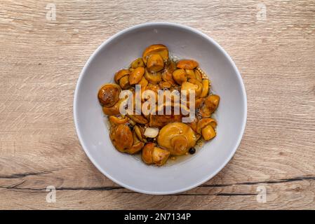 Funghi sottaceto in aceto in una piccola ciotola sul tavolo. Foto Stock