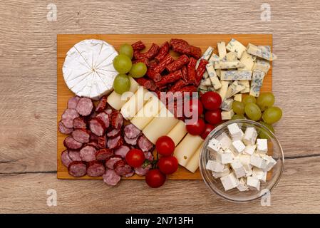 Tavola di legno con pezzi di carne, feta e verdure, sul bancone della cucina, vista dall'alto. Foto Stock