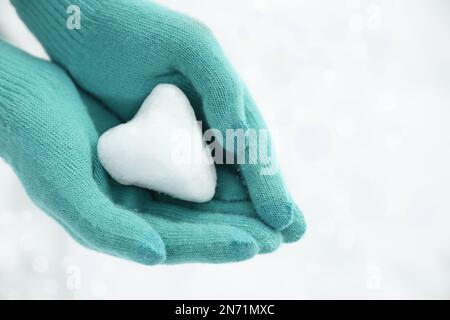 Donna che tiene la palla di neve a forma di cuore in mano, primo piano Foto Stock