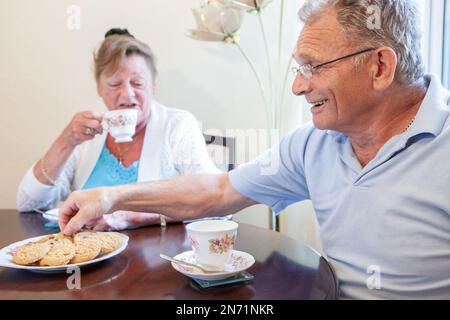 Pensione: Tè e biscotti. Una coppia britannica anziana seduta per godersi una pausa e l'una l'altra compagnia. Da una serie di immagini correlate. Foto Stock