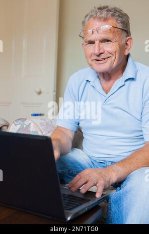 Pensione: Silver Surfer. Un uomo anziano che utilizza il suo computer portatile a casa. Da una serie di immagini correlate. Foto Stock