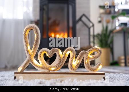 Decorazioni di San Valentino vicino a stufa con camino e legna da ardere. Accogliente casa cuore in interni con vaso piani, giorno di San Valentino in famiglia amore nido. Foto Stock