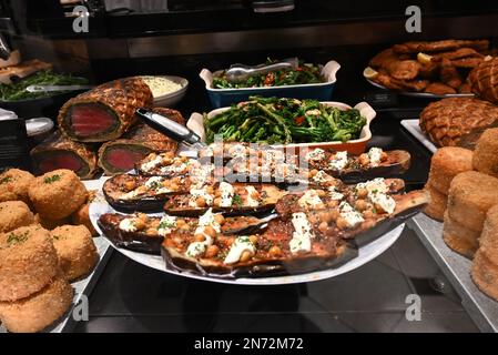 Le sale da pranzo Harrods servono delizie culinarie da tutto il mondo preparate ogni giorno al momento. I piatti che vedete nel fresco mercato Hall sono tutti realizzati in-house dal team di 150 chef. Sotto la guida del capo chef esecutivo Andy Cook e del capo chef senior Andy Ward (le cui carriere hanno incluso stints con Gordon Ramsey e Marcus Waering, rispettivamente), le cucine in loco offrono tutto, dai migliori panini con salsiccia al manzo Wellington, il tutto realizzato con ingredienti delle sale da cucina. Foto Stock