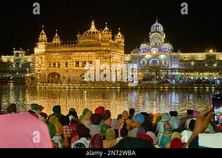 Celebrazioni notturne del Tempio d'Oro riflesse in un lago sacro, Amritsar Foto Stock