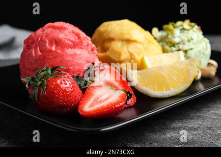 Cucchiai di gelato alla fragola, al limone e al pistacchio serviti sul tavolo, primo piano Foto Stock