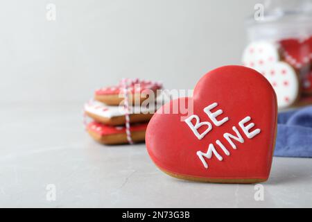 Delizioso biscotto a forma di cuore con frase Be Mine su tavolo leggero, spazio per il testo. San Valentino Foto Stock