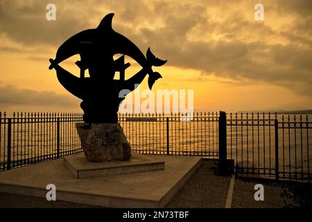 Rethymno città Grecia delfini statua architettura punto di riferimento con silhouette tramonto Foto Stock