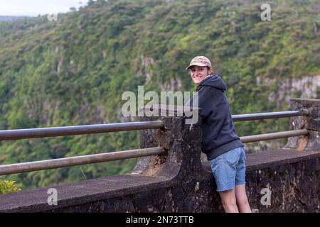 Una giovane donna che gode della vista panoramica del Black River Gorges National Park, Gorges Viewpoint a Mauritius. Si estende su un'area di 67,54 km che comprende una foresta umida di altopiano, una foresta di pianura più secca e un'brughiera paludosa. Foto Stock