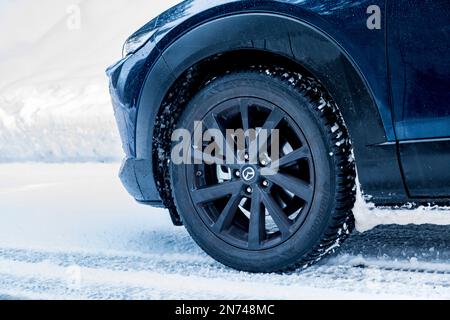 Italia, Veneto, Belluno, dettaglio di una ruota con cerchio in lega e pneumatico invernale su crossover Mazda, Dolomiti Foto Stock