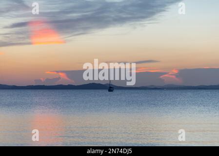 Vista dello yacht a vela di fronte all'orizzonte al tramonto sulla spiaggia di Almanarre vicino a Giens, Francia Foto Stock