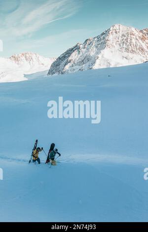 Due snowboarder professionisti e sciatori esplorano e sciano una grotta di ghiaccio sul ghiacciaio Pitztal, Pitztal, Tirolo, Austria Foto Stock