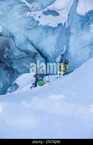 Due snowboarder professionisti e sciatori esplorano e sciano una grotta di ghiaccio sul ghiacciaio Pitztal, Pitztal, Tirolo, Austria Foto Stock