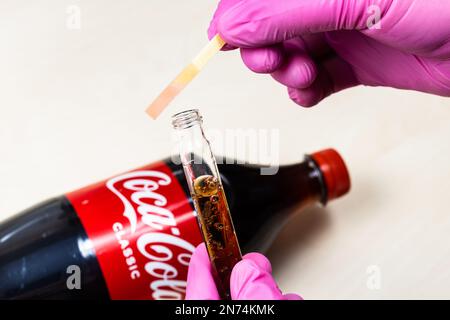 Mosca, Russia - 12 gennaio 2023: Misurazione del livello di pH della Coca Cola Classic, carta di tornasole rosa mostra acidità. Coca-Cola (Coca-Cola) è un dr morbido carbonato Foto Stock