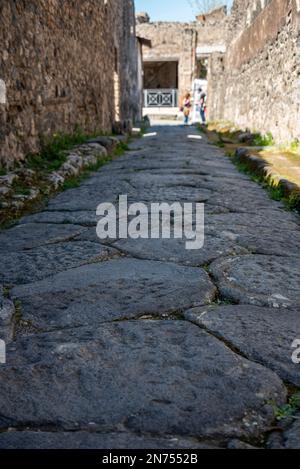 Una bella strada acciottolata tipica nell'antica città di Pompei, nel sud dell'Italia Foto Stock