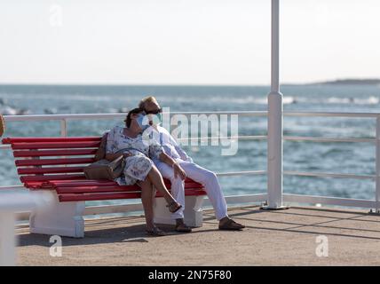 coppia anziana seduta sulla panca e con il viso protettivo Foto Stock