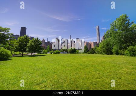 Il grattacielo di Midtown Manhattan si erge dietro il verde fresco di Roosevelt Island. Foto Stock