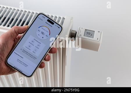 Mano da uomo con Apple iPhone, display, FRITZ! App Smart Home, radiatore con termostato per radiatore WLAN FRITZ! DECT 302, il display visualizza 1ö °C., sfondo bianco, immagine dell'icona, smartphone per il controllo del riscaldamento, casa intelligente, rete, digitale, Foto Stock