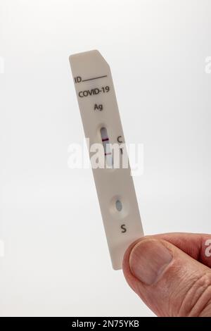 Cassetta per analisi dell'antigene Rapid SARS-COV-2, per uso maschile, con risultati positivi, fondo bianco, Foto Stock