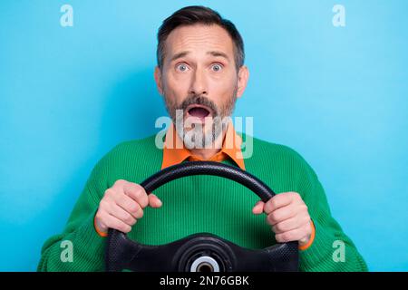 Foto ritratto di maturo bel mister tenere volante ansioso espressione viso indossare alla moda verde look isolato su sfondo di colore blu Foto Stock