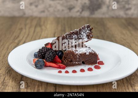 Delizioso dessert di torta al cioccolato senza farine servito con bacche nere e mirtilli. Foto Stock