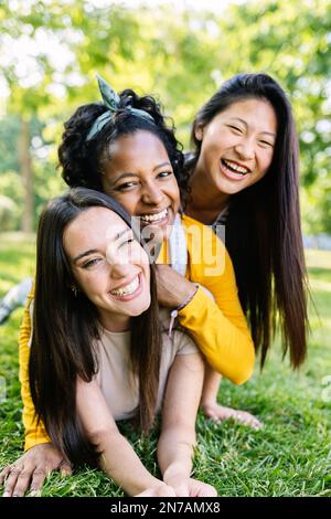 Ritratto verticale di tre amici femminili multirazziali in una pila all'aperto Foto Stock