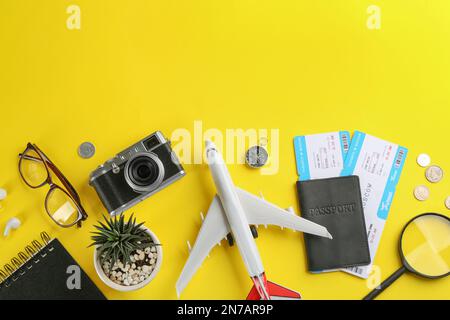 Composizione piatta con velivolo giocattolo e oggetti da viaggio su sfondo giallo. Spazio per il testo Foto Stock