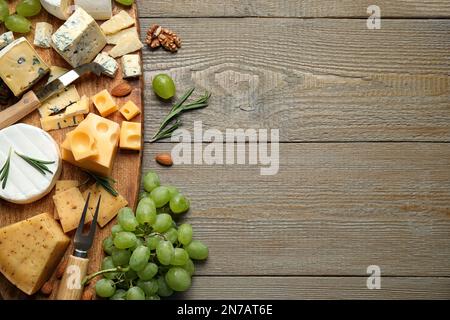 Piatto di formaggi con coltello specializzato e forchetta su tavolo di legno, piatto. Spazio per il testo Foto Stock