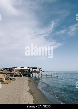Ombrelloni di paglia su una spiaggia di sabbia sul mare Foto Stock