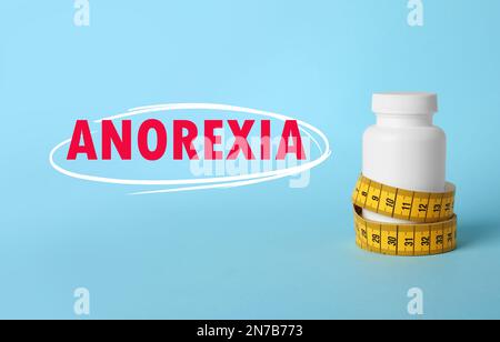 Concetto di anoressia. Bottiglia di pillole di perdita di peso con metro a nastro su sfondo azzurro Foto Stock