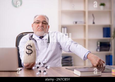 Medico anziano in concetto di remunerazione Foto Stock