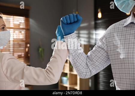 Le persone si salutano a vicenda battendo pugni invece di stretta di mano in ufficio, primo piano Foto Stock