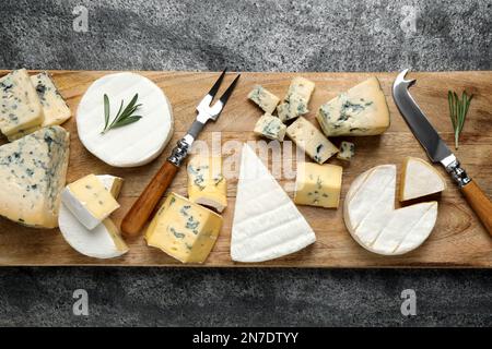 Piatto di formaggi con coltello specializzato e forchetta su tavolo grigio, vista dall'alto Foto Stock