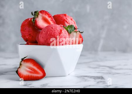 Gelato alla fragola in ciotola su un tavolo di marmo bianco. Spazio per il testo Foto Stock