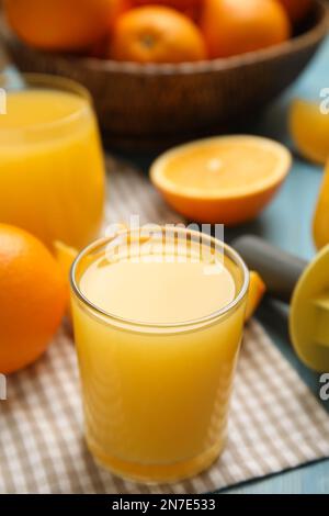 Succo di frutta appena fatto, arance e alesatore su tavolo blu Foto Stock