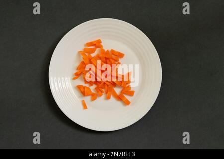 julienne di carote tritate su un piatto su uno sfondo scuro Foto Stock